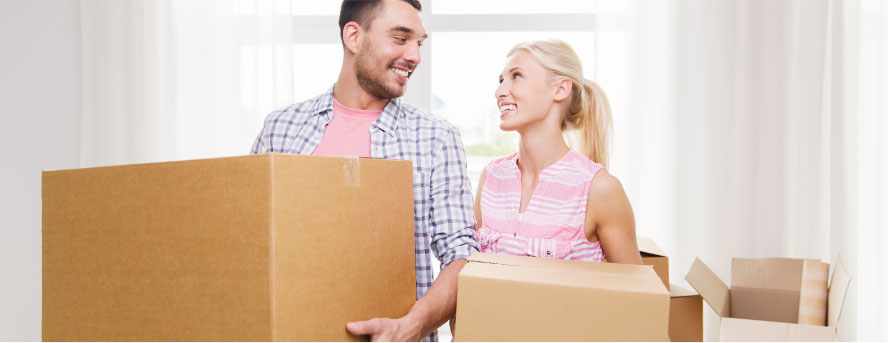 photo of a couple smiling at each other while carrying packing boxes