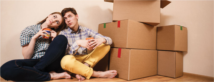 photo of a couple finished packing sitting next to the boxes on the floor