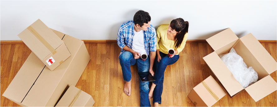 photo of a happy couple sitting on the floor having some hot coffee after packing