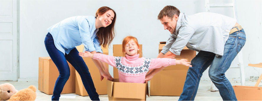 happy family with their daughter comming out of a box smiling with her hands up