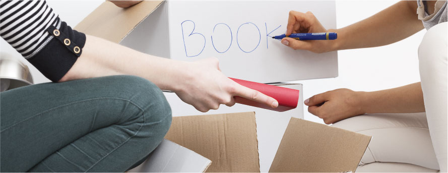 photo of two women packing home items and marking the boxes